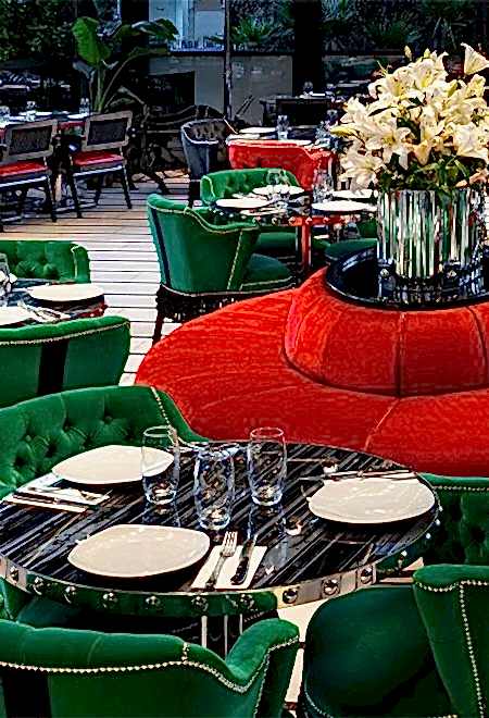 Nusr-Et Etiler’de şık yemek düzeni, cesur yeşil ve kırmızı kadife sandalyeler, siyah mermer masalar ve canlı, lüks bir atmosfer sunuyor.